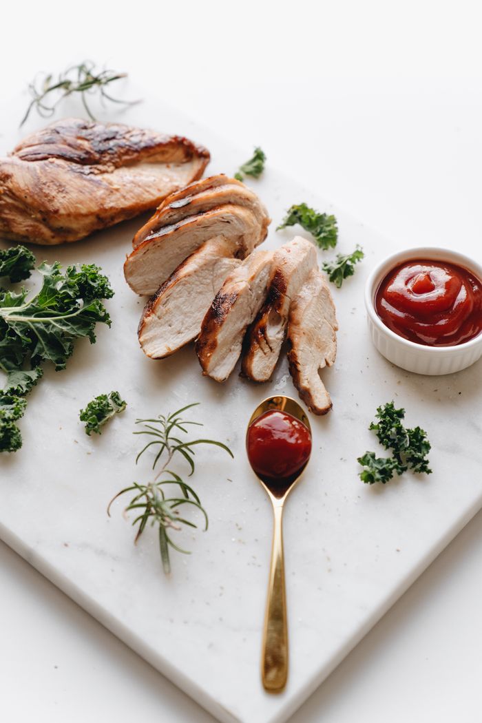 Delicious sliced chicken breast with herbs and ketchup on a marble slab.